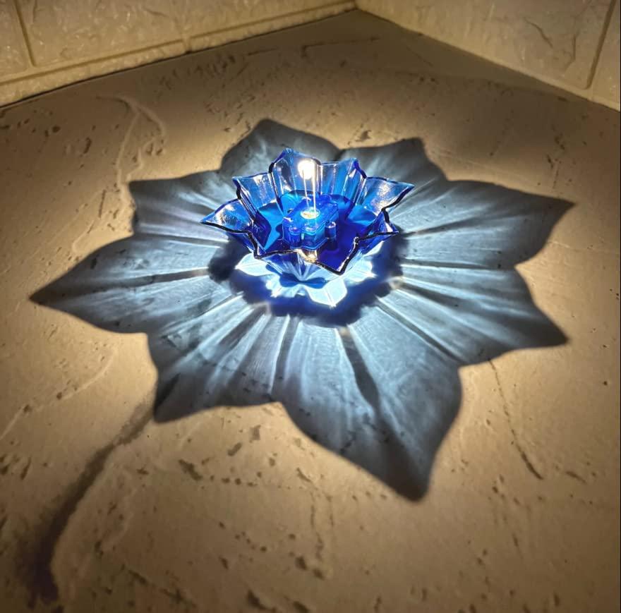 Blue electric water sensor diyas casting a glowing floral shadow on textured surface