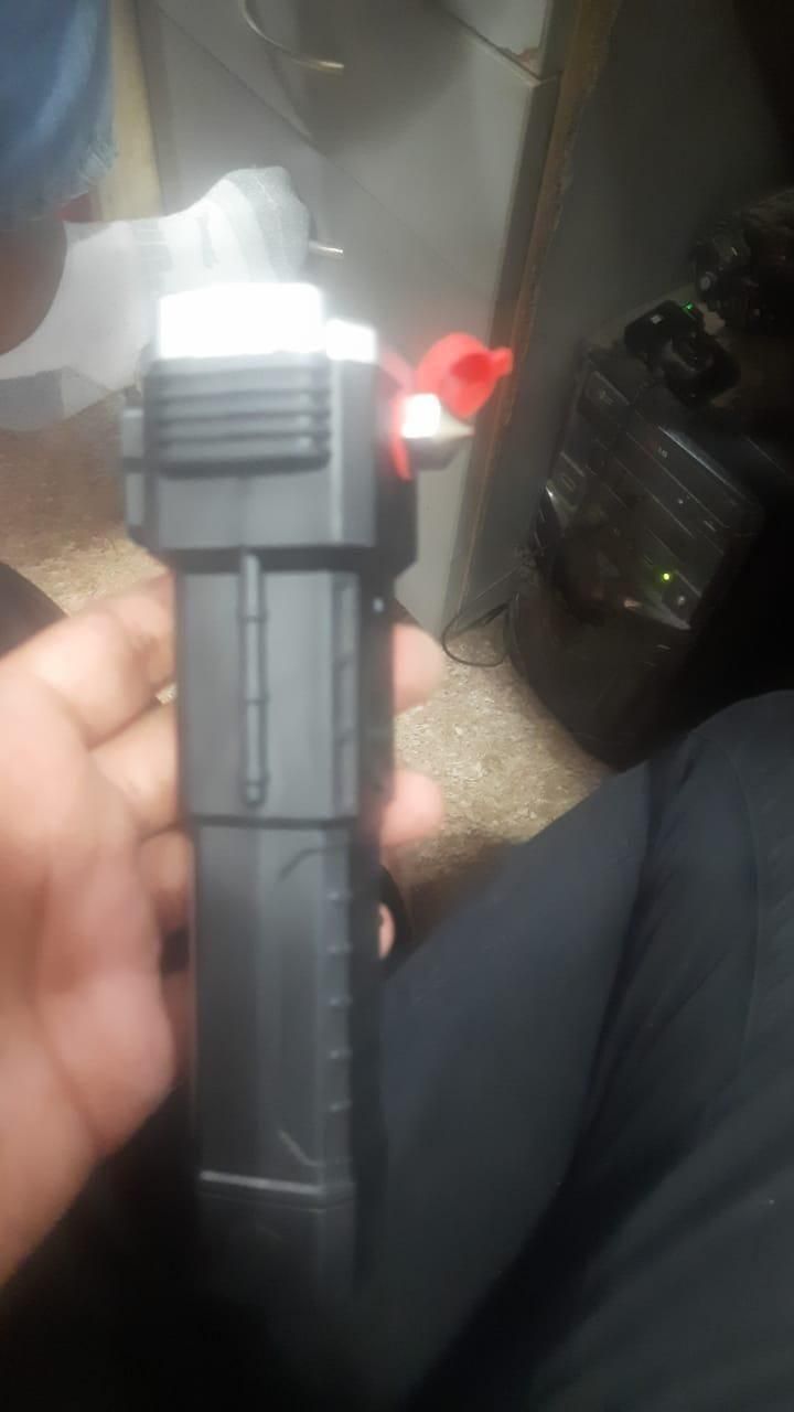 Hand holding a portable rechargeable LED flashlight emitting bright white light indoors